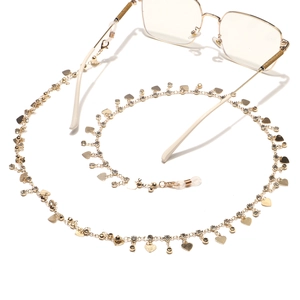 Chaîne à lunettes dorée avec breloques cœurs et strass blancs sur fond blanc