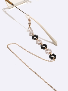 Elegant black and white pearl flower glasses chain with golden links on white background
