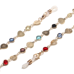Golden eyewear chain with colorful crystals and rose-patterned heart charms on white background