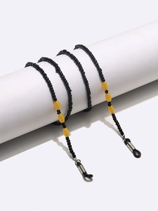 Handmade eyeglass chain with black beads and yellow accents on white display