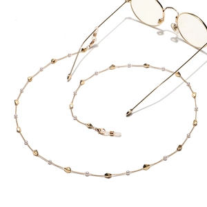 Elegant gold eyeglasses chain with white pearls and geometric beads on white backdrop