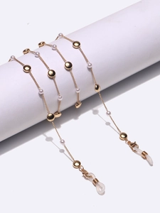 Elegant gold glasses chain with white pearls and metal discs on a white background