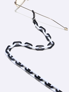 Acrylic black and white U-shaped eyeglass chain with gold frame glasses on grey background