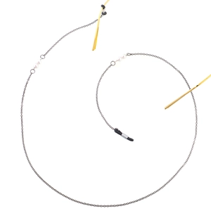 Detail of pearl eyewear chain featuring gold bars, black metal links and rubber loops