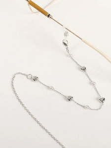 Détail de chaîne à lunettes argentée avec pendentifs cœur, perles et boucles silicone