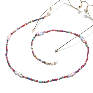 Detailed close-up of colorful seed beads and square letter beads on a golden eyewear chain