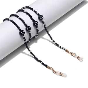 Close-up of black and white beaded eyeglass chain with smiley faces and gold lobster clasp