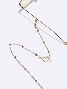 Golden diamond geometric glasses chain with metallic beads on white background