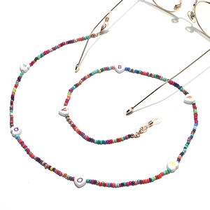 Detail of colorful beads and LOVE heart charms on eyewear chain with gold metal hooks