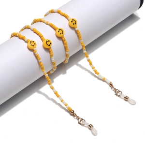 Detail of yellow and white beaded eyewear chain with smiley face pendant and golden clasps