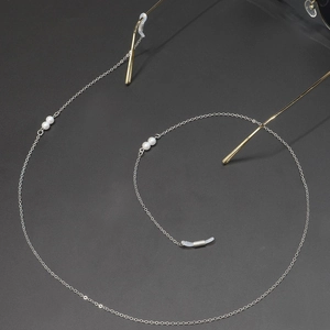 Detail of silver glasses chain with white pearls and anti-slip silicone loops on dark gray