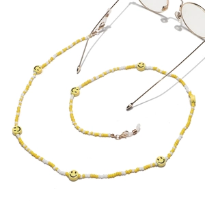 Close-up of yellow and white beaded glasses chain with smiley face charms and lobster clasps