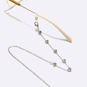 Détail d'une chaîne de lunettes argentée avec pendentifs en cœur et boucles en silicone souple