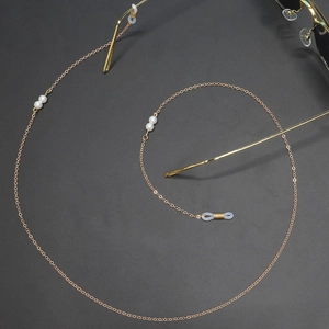 Detailed macro of gold glasses chain with elegant white pearls and clear rubber grips
