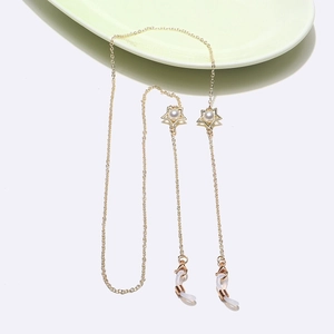 Chaîne à lunettes dorée avec breloques étoiles et perles sur fond blanc épuré