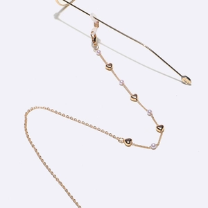 Chaîne à lunettes dorée avec perles violettes et breloques cœur sur fond blanc