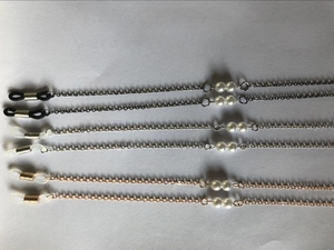 Detail of thin eyewear chains in black, gold and silver with white pearl accents