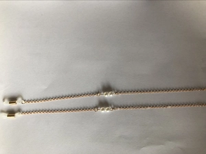 Detailed view of dual golden glasses chain with white pearls and silicone ends