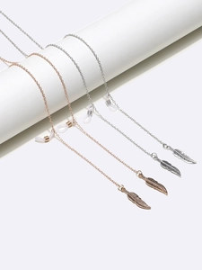 Detailed macro view of metal eyewear chains with leaf charms in silver and rose gold