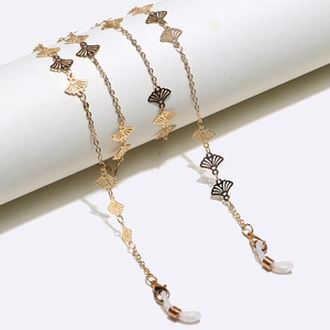 Golden fan-shaped eyewear chain with cutout ginkgo leaf pendants on a white column