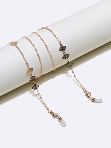 Detail of gold eyewear chain with black fan-shaped pendants wrapped on a white pillar