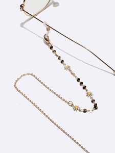 Gold glasses chain with white daisy pendants and black sequins on a white background