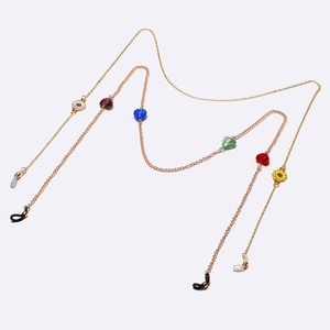 Golden eyewear chain set with colorful heart beads and daisy charms on white background