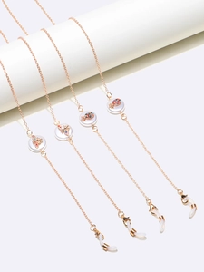 Golden eyewear chains with pearl pendants and insect charms on a white display