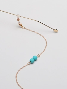 Macro shot of gold glasses chain with turquoise beads and adjustable silicone loops