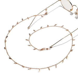 Minimalist gold eyeglass chain with delicate metal leaf pendants on white background
