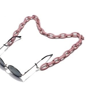 Detail of pink chunky acrylic chain links with retro round black sunglasses on white