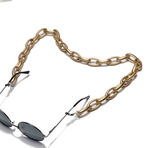 Macro detail of matte gold oversized link chain with adjustable silicone loops for eyewear