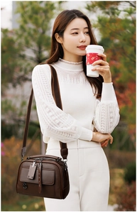 Close-up of brown textured leather bag with multiple zippers and woven shoulder strap