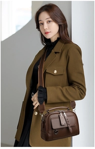 Brown leather crossbody bag detail featuring a wide strap and silver metallic rivets