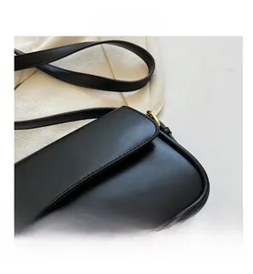 Detail view of black leather crossbody bag featuring gold hardware and magnetic closure