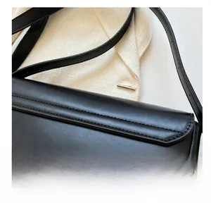 Detailed close-up of neat stitching and fine leather texture on black shoulder bag