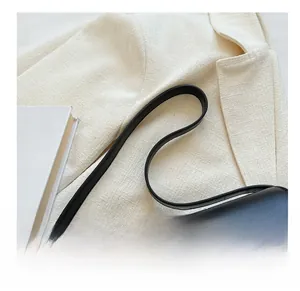 Close-up of sleek black leather handbag handle with a stylish white tweed jacket backdrop
