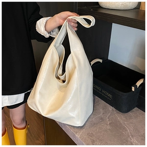 Detailed shot of large cream faux leather hobo bag with soft pleated texture and glossy finish