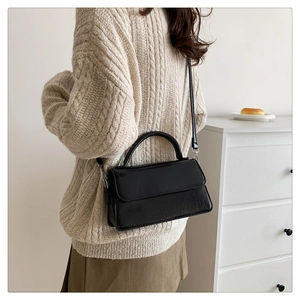 Detail of minimalist black crossbody bag with litchi texture and silver metal hooks