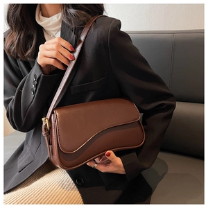 Detail of dark brown leather crossbody bag featuring unique wavy edge flap and metal clasp