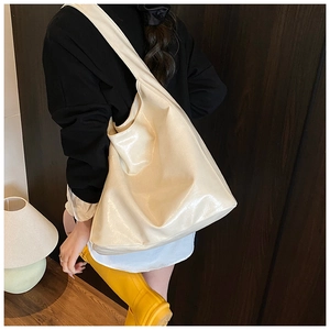 Close-up of a large cream glossy leather tote bag showing soft texture and spacious design