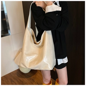 Detail of creamy white large tote bag showing glossy texture and wide shoulder strap