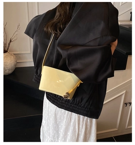 Détail du sac seau jaune à motif litchi avec un pendentif en forme de cœur en métal