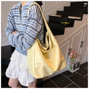 Detail of a creamy yellow minimalist hobo tote bag in PU leather showing slouchy texture