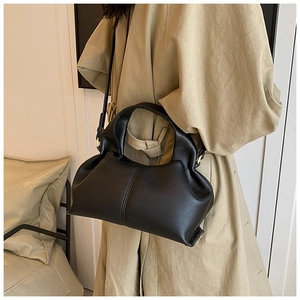 Detail of black pebbled leather texture on a slouchy crossbody cloud bag with curved handle