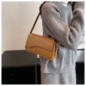Brown leather baguette bag with a wave flap shown on model with grey knit outfit