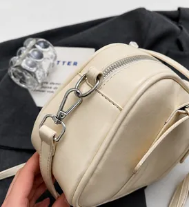 Primer plano de hebillas de metal plateado y textura de cuero en un bolso beige bowling