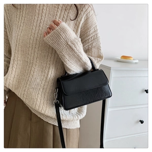 Detail of black crossbody bag with pleated leather texture and silver hardware
