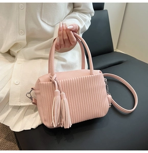 Détail du sac à bandoulière rose avec plis accordéon et longs glands en cuir