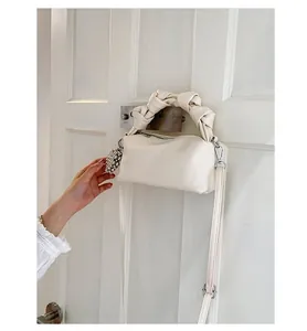 Close-up of off-white leather box bag with knotted handle and pearl grape charm